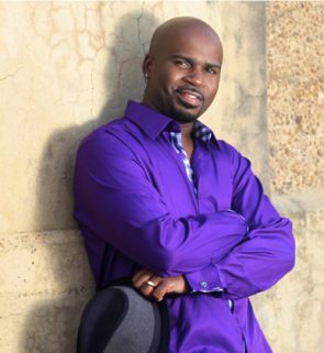 Photo of comedian Rahn Hortman leaning against a wall.